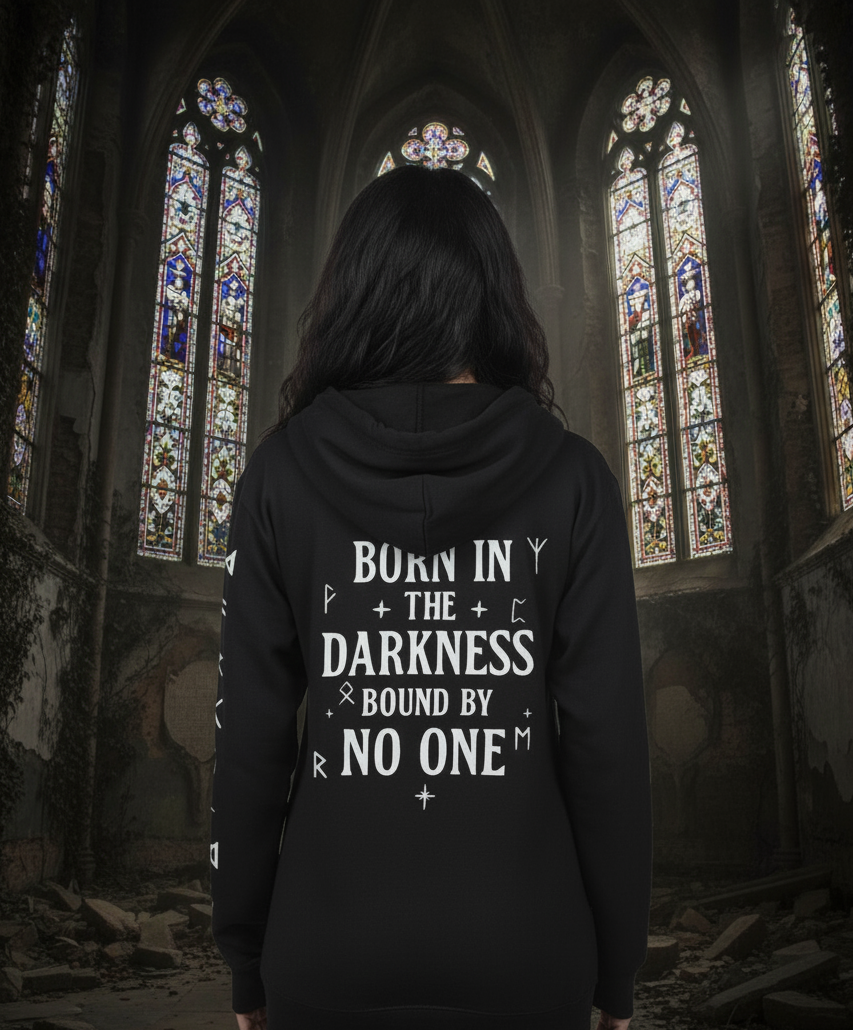Person wearing a black hoodie with text in a dark, cathedral-like setting