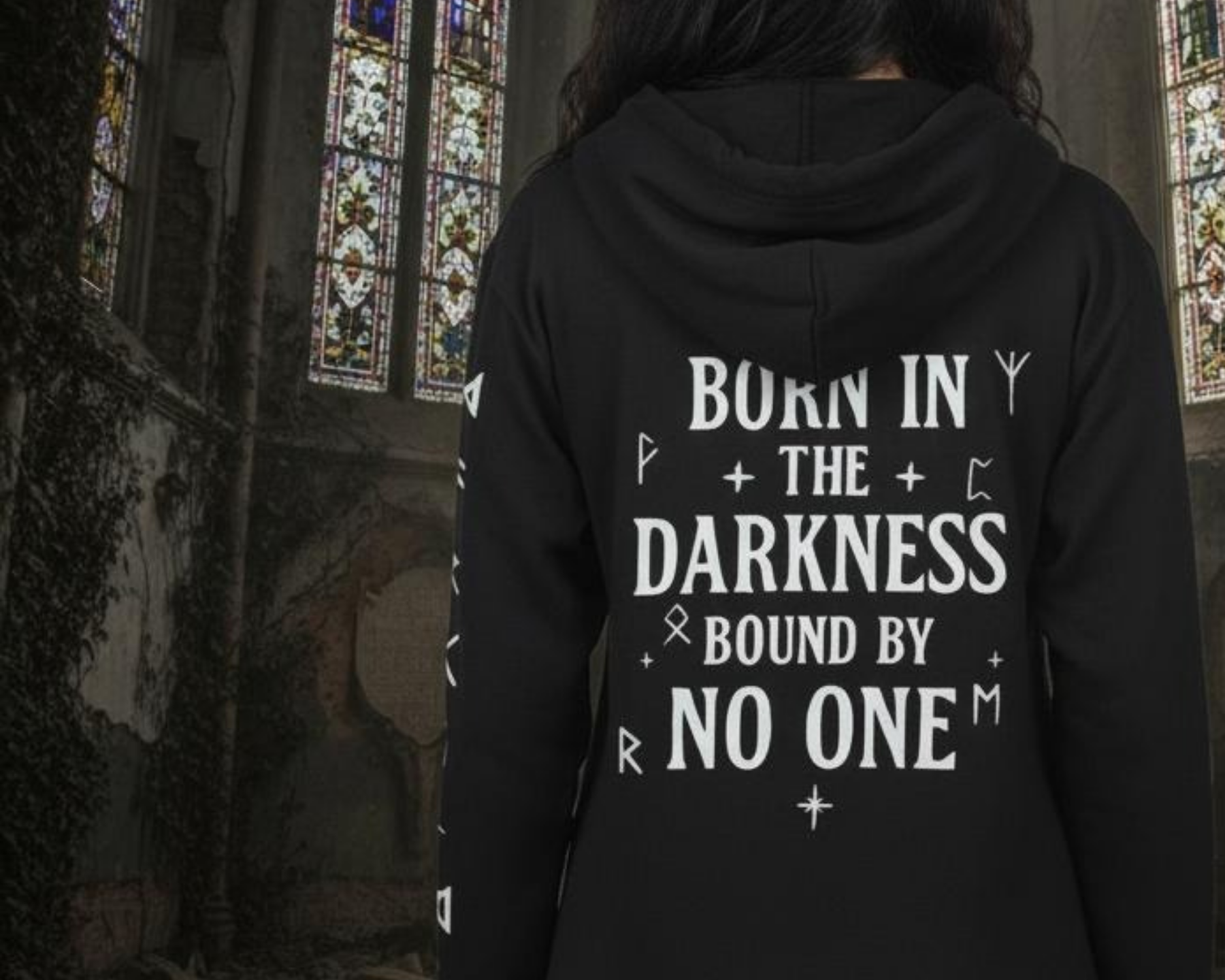 Person wearing a black hoodie with text in a gothic setting with stained glass windows.